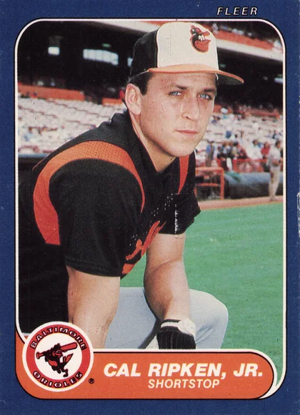 Front of 1986 Fleer Fleer Cal Ripken, Jr. #284, portrait photo of a player in a black and orange Baltimore Orioles uniform and cap with the Orioles bird logo, standing on a field with stadium…