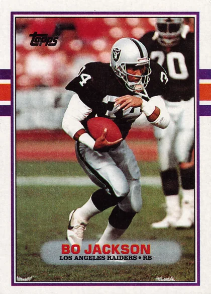 Front of 1989 Topps Bo Jackson #269, portrait-orientation front with purple border and orange/white stripe accents on left and right edges. Photo shows a Raiders player in black and…