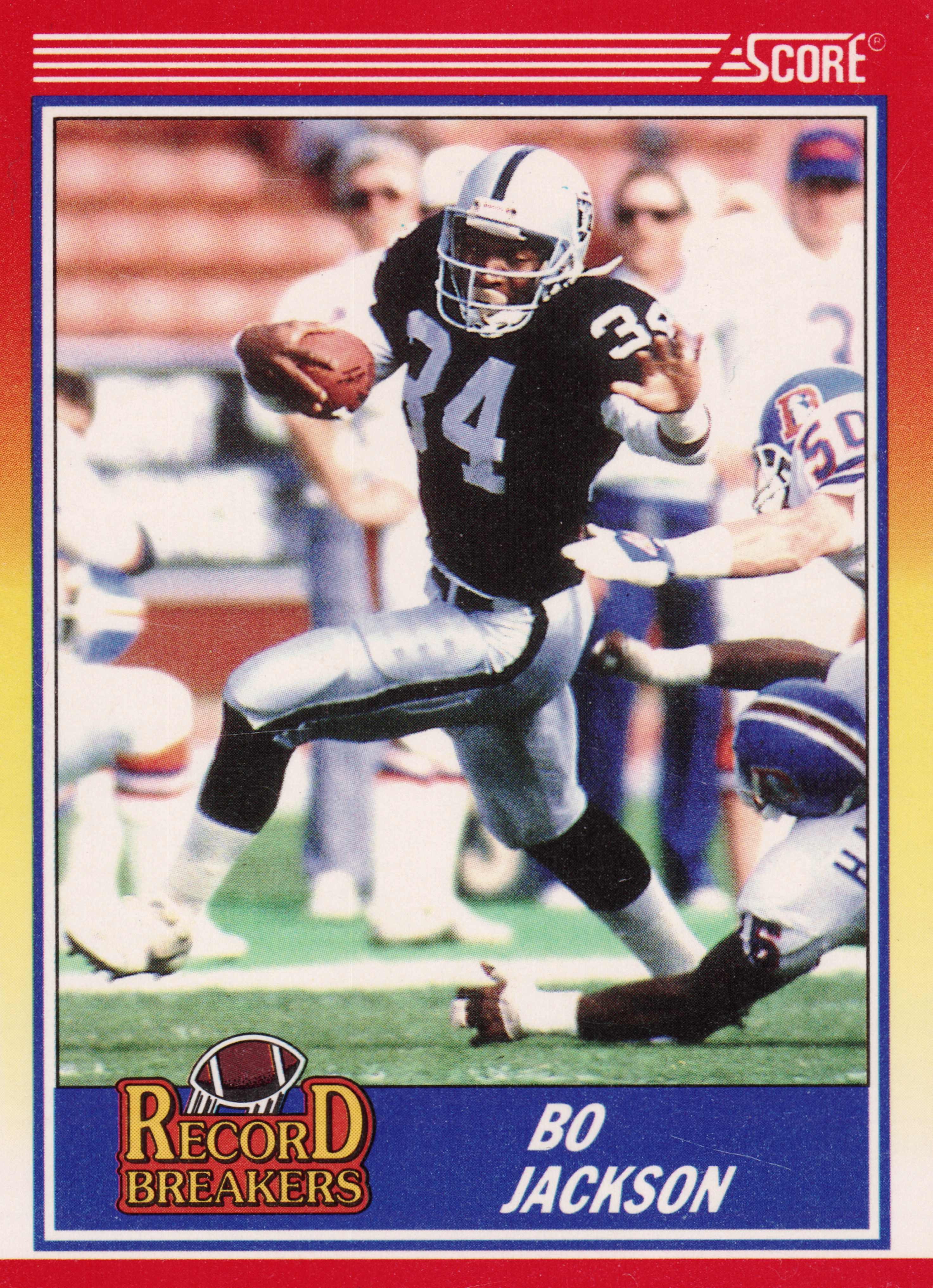 Front of 1990 Score Record Breakers Bo Jackson #591 1990 Score Record Breakers Bo Jackson #591, action photo of a player in a black and silver uniform (number 34 visible) carrying a football, evading defenders in white and blue uniforms. Red…