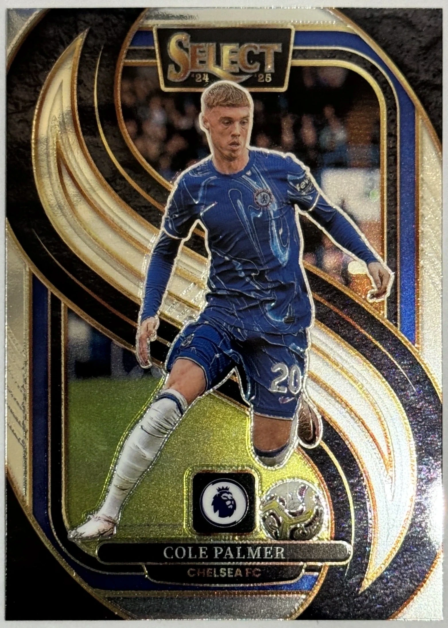 Front of 2024-25 Panini Select Premier League Soccer Cole Palmer #182 Mezzanine Ice Prizm, a soccer trading card featuring a cutout of Cole Palmer in a blue Chelsea FC jersey with the number 20 on his shorts, set against a swirling gold…