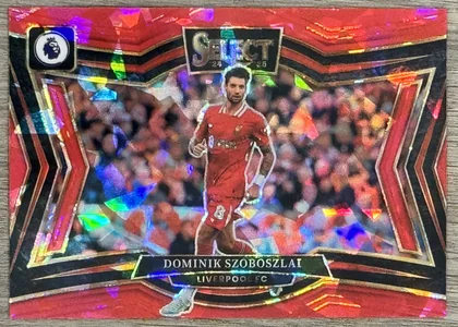 Front of 2024-25 Panini Select Premier League Soccer Dominik Szoboszlai #219 2024-25 Select Premier League Soccer #219 Dominik Szoboszlai Red Prizm, a soccer trading card with a red and black chevron border and a holographic prizm background. The central image shows a player in a red Liverpool…