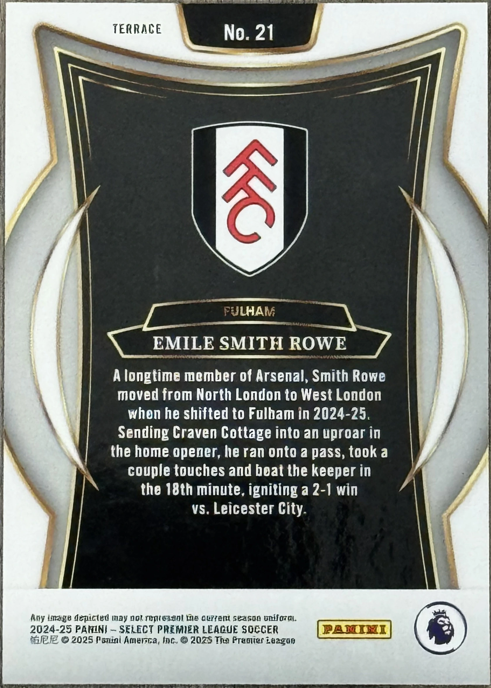 Back of 2024-25 Panini Select Premier League Soccer Emile Smith Rowe #No. 21 Terrace Silver, the card is upside down. It features a black background with a white and gold die-cut border. In the center is the Fulham FC crest (a white shield…