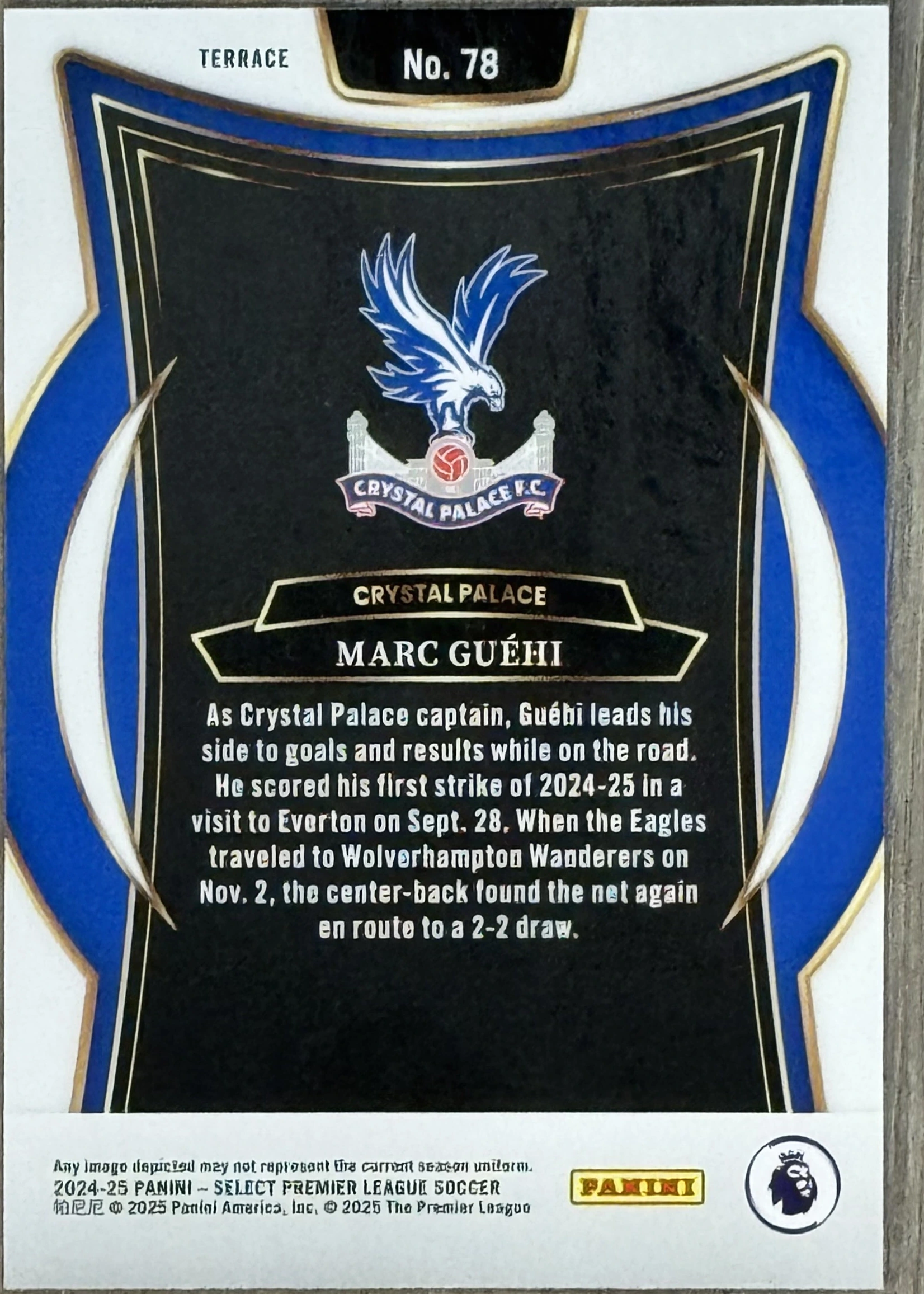 Back of 2024-25 Panini Select Premier League Soccer Marc Guéhi Terrace Blue Prizm, the back of a soccer trading card featuring a black central panel with a blue and white border. At the top is the Crystal Palace F.C. crest…