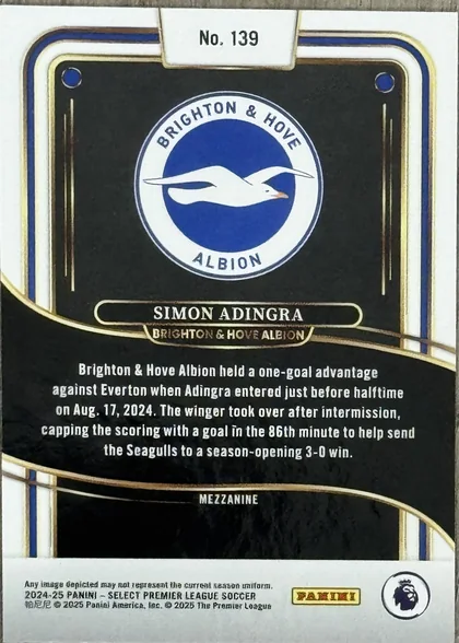 Back of 2024-25 Panini Select Premier League Soccer Simon Adingra #139 Mezzanine Prizm, the back of a trading card, oriented upside down. It features a black background with white and blue borders and gold accents. At the top (when…